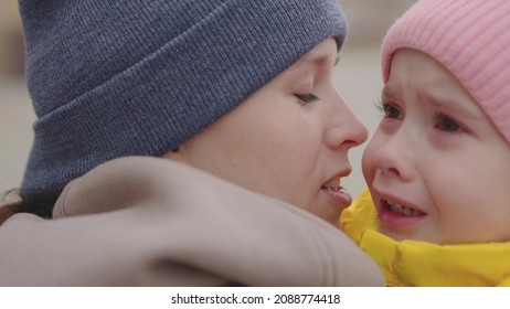 tears from wet eyes flow from the little child, the mother soothes and hugs the capricious kid in park, upset face of baby girl, caring mother consoles tantrum of the sad daughter, to experience pain