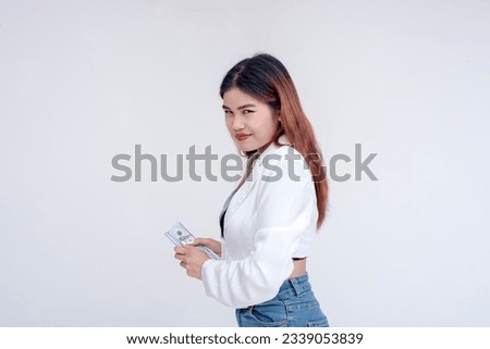 A teasing and taunting young woman smirking at the camera while holding her money away. Isolated on a white background.