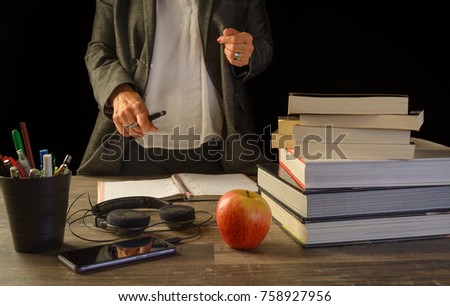 a teatcher in front a study table desk with books a open sketch book and pencil bucket, university study, school.