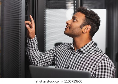 Tech Expert. Positive IT Guy Using Laptop And Examining Server Room