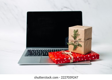 Tech gifts for Christmas for the tech-obsessed person. Gadgets and devices Xmas gift ideas. Laptop with Christmas Gift boxes on the table - Powered by Shutterstock