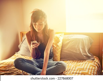 Tech Savvy Asian Teen Girl Using Smart Phone In Bed Room