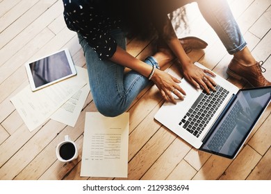 Tech savvy and industrious. Shot of an unrecognizable female designer working on her laptop while sitting on the floor in her office. - Shutterstock ID 2129383694