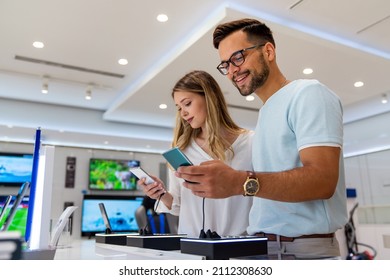 Tech shopping device gadget concept. Happy young people buying a new smartphone in mobile shop. - Shutterstock ID 2112308630