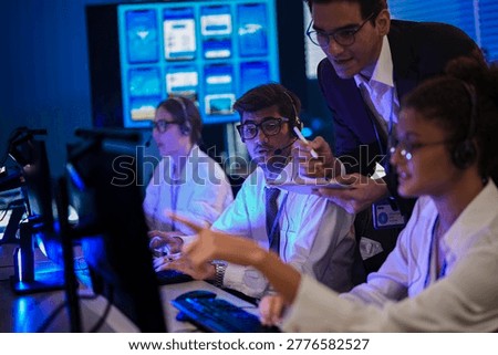 Tech support and software development team working in a modern operations center at night, reviewing mobile application UI UX grids on digital screens.