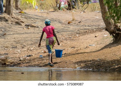 TECHIMAN, GHANA - JAN 15, 2017: Unidentified Ghanaian woman carries a blue bucket of water on the Washing Day, which is every Sunday