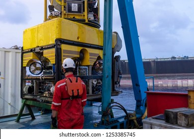 A techinician standing nearby Remoted Operated Vehicle (ROV) hanging on Launch & Recovery System (LARS) for underwater pipeline survey and inspection nearby Floating Storage Offloading (FSO) vessel.