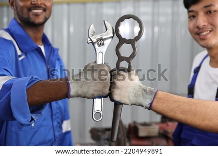 Technicain mechanic hands holding wrench and make fist bumping celebrate successful together completed deal commitment at garage. Maintenance automotive and inspecting vehicle part concept