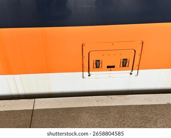 a technical access panel on the side of a high-speed train. its shape resembles a face