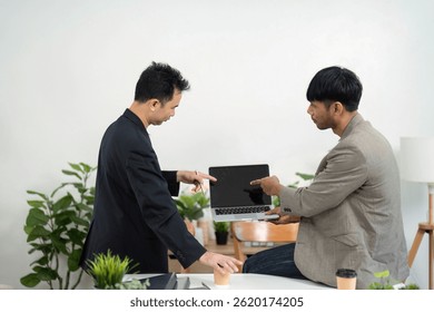 Technical Discussion and Problem Solving. Colleagues analyzing a laptop screen during a meeting.