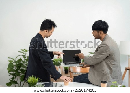 Technical Discussion and Problem Solving. Colleagues analyzing a laptop screen during a meeting.
