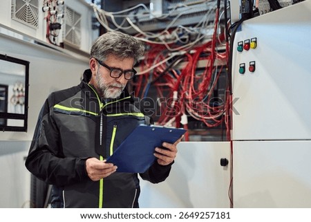 Technical engineer checking control panel with cables and switches at facility