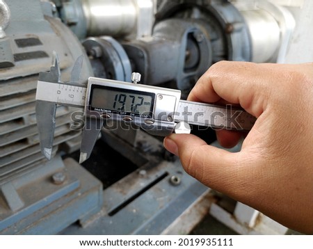 A technical engineer is holding a vernier caliper for support in measuring machine tools with high accuracy.