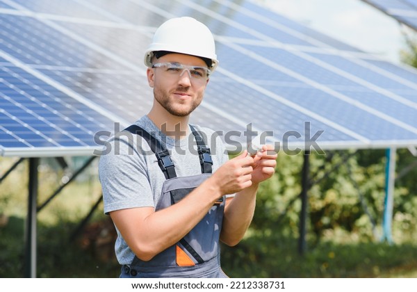 Technical expert in solar\
photovoltaic panels, remote control performs routine actions to\
monitor the system using clean renewable energy in the hand a light\
bulb