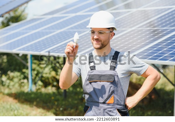 Technical expert in solar\
photovoltaic panels, remote control performs routine actions to\
monitor the system using clean renewable energy in the hand a light\
bulb
