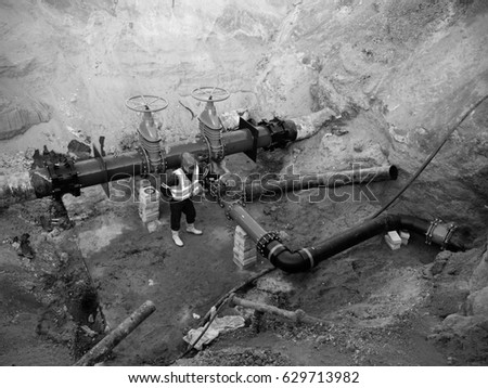 Technical expert underground at  gate valve on 500mm drink water pipes joined with  old pipeline system. Check of repaired piping before covering by clay. Asphalt isolation 