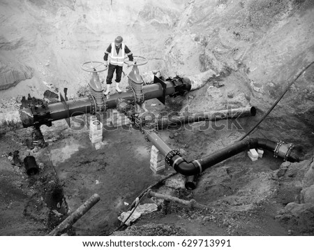 Technical expert underground at  gate valve on 500mm drink water pipes joined with  old pipeline system. Check of repaired piping before covering by clay. Asphalt isolation 