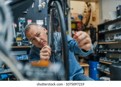 Technical expertise taking care Bicycle Shop. Repair technician bicycles was repaired gear bike shop. Friendly and competent bicycle mechanic in a workshop repairs a bike - Powered by Shutterstock