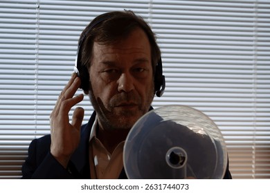 Technical intelligence. A man uses a highly sensitive microphone and headphones for remote listening