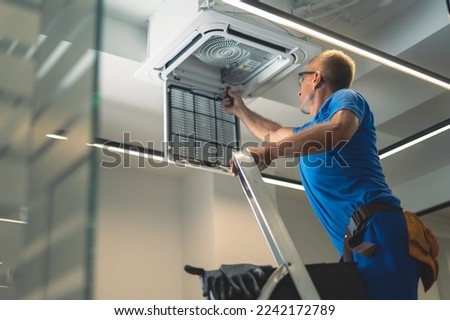 Technical maintenance worker repairs the air conditioning system