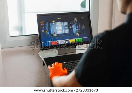 Technical operator checking wheel alignment and divergence in a professional workshop.