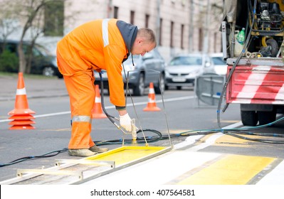 Technical Road Man Worker Painting And Remarking Pedestrian Crossing Lines On Asphalt Surface Using Paint Sprayer Gun During Capital Street Pavement Maintenance Works