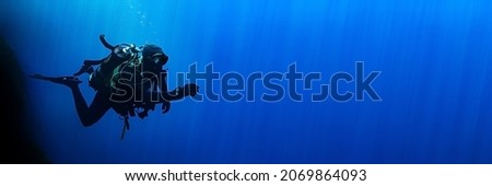 Technical scuba diver in a horizontal position with sun rays blue background. High quality photo. Can be used as a background for a banner