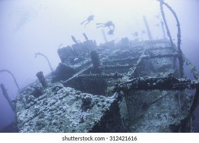 Technical Scuba Divers Exploring A Large Deep Underwater Shipwreck