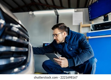 A technical service worker crouching and using tablet to check on the car. - Powered by Shutterstock