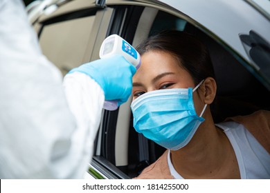 Technical staff using thermometer measure people with test drive thru.PPE medical using tool for check temperature with driver for prevent and seperate illness person. - Powered by Shutterstock