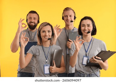 Technical support call center. Team of friendly operators showing ok gesture on yellow background