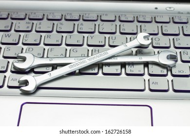 technical support concept - spanners on computer keyboard