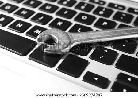 Technical support concept. Wrench on laptop keyboard, closeup
