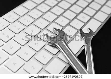 Technical support concept. Wrenches and keyboard on black background, closeup