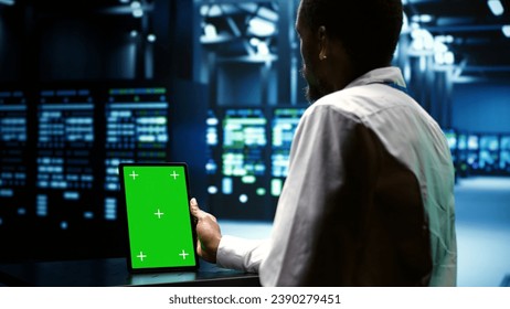 Technical support executive troubleshooting data center mainframes performance trends. Manager using chroma key tablet to spot high tech establishment operational issues causing hardware to slow down