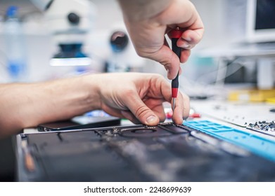 Technical support and fixing gadgets problems. Servicing, repairing, cleaning, maintaining computers. Repair shop. Hardware maintenance. Male technicians fixing disassembled laptop parts. 