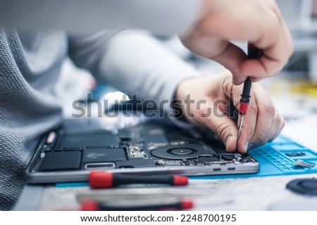 Technical support and fixing gadgets problems. Servicing, repairing, cleaning, maintaining computers. Repair shop. Hardware maintenance. Male technicians fixing disassembled laptop parts. 