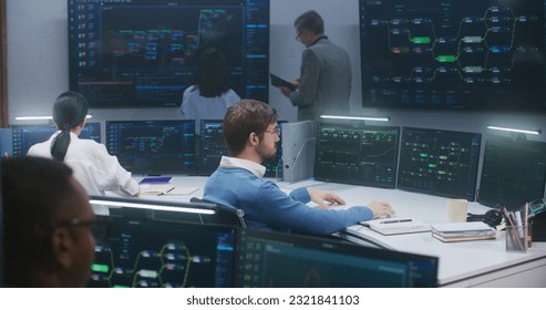Technical support specialists sit at computers with displayed blockchain network map and server data. Big data scientists work in monitoring room. Big screens on the wall. Concept of cyber security. - Shutterstock ID 2321841103