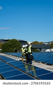 Technical team of solar engineers checking and discussing renewable energy installation on a commercial building rooftop