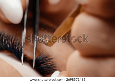 Technician is applying eyelash extensions with precision tools, emphasizing the detailed beauty process and the artistry involved in enhancing natural lashes