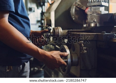 Technician asia worker using turning lathe machine for metalworking in workshop factory