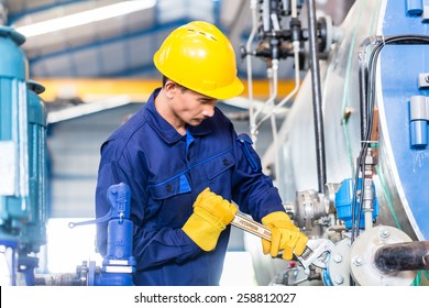 Technician In Asian Factory At Machine Maintenance Working With Wrench