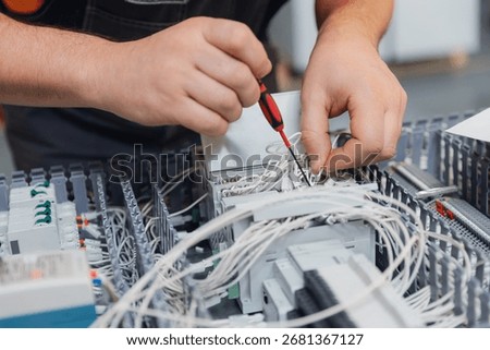 Technician assembling electrical components in industrial factory.