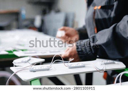 Technician assembling led light modules on panel for electronics manufacturing workshop and product.