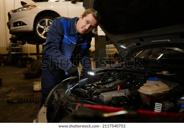Technician automotive checking\
car in the garage. Auto mechanic working with engine in garage, car\
service technician repairing customer care at automobile service\
center.