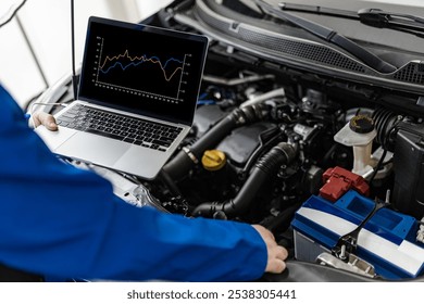 A technician in a blue uniform examines an engine while using a laptop to review performance data. This occurs in a well-lit automotive workshop. - Powered by Shutterstock