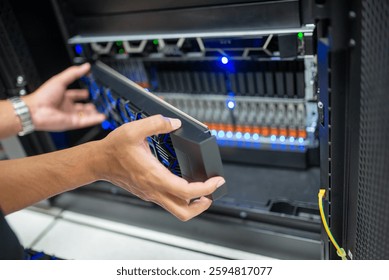 A technician is carefully installing a data storage device in a server room rack. The modern infrastructure supports efficient data management and storage solutions.