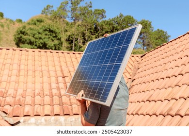 Technician carrying a solar panel on a residential roof under bright sunlight. Illustrates companies promoting clean and renewable energy solutions through solar power.