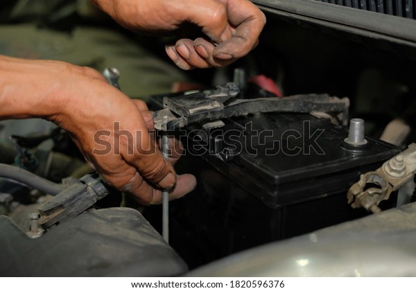 technician changing car battery in auto repair\
garage shop