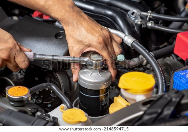 Technician changing engine oil filter. Car\
maintenance concept.